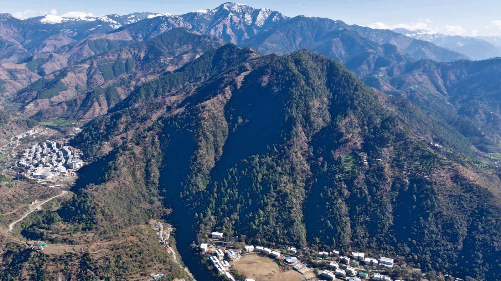 IIT Mandi's campuses set among forested hills below snow-capped mountains.